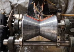 V-groove roller induction hardening process showing localized heating along the groove with a custom-profiled induction coil.