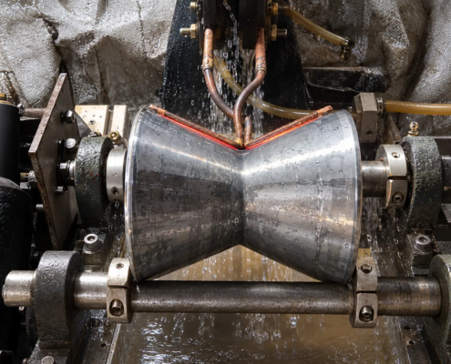 V-groove roller induction hardening process showing localized heating along the groove with a custom-profiled induction coil.